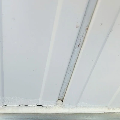 Korrodierte Stahlpaneel-Wände, die mit der Zeit an den Fußleisten und in den Zwischenräumen Verschmutzungen und Schimmel angesetzt haben.